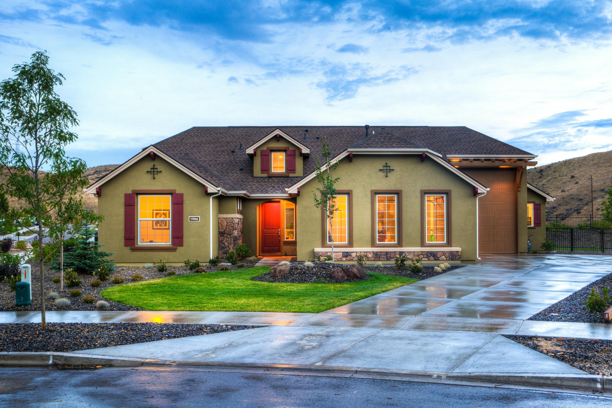 A large house with a spacious driveway leading up to its entrance, surrounded by greenery.