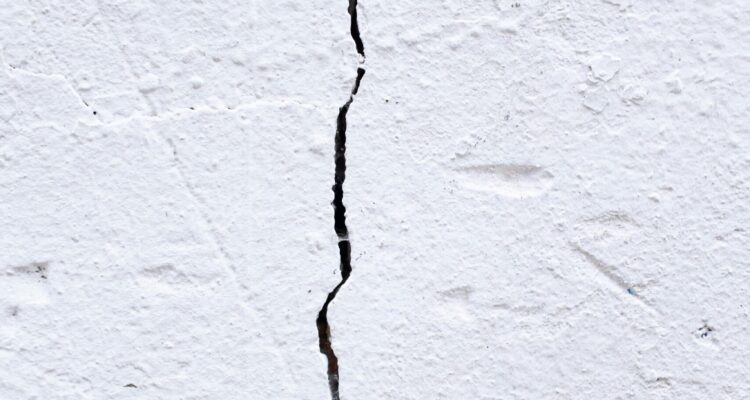 A close-up view of a white wall featuring a prominent crack running through its surface.