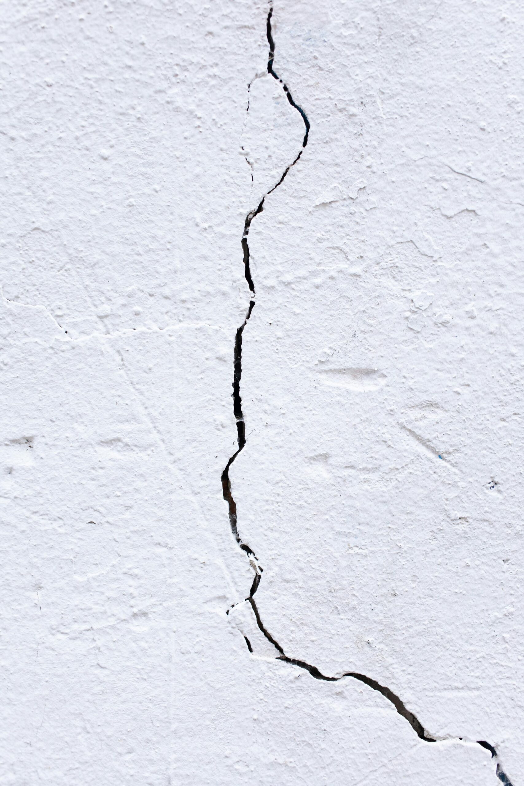 A close-up view of a white wall featuring a prominent crack running through its surface.