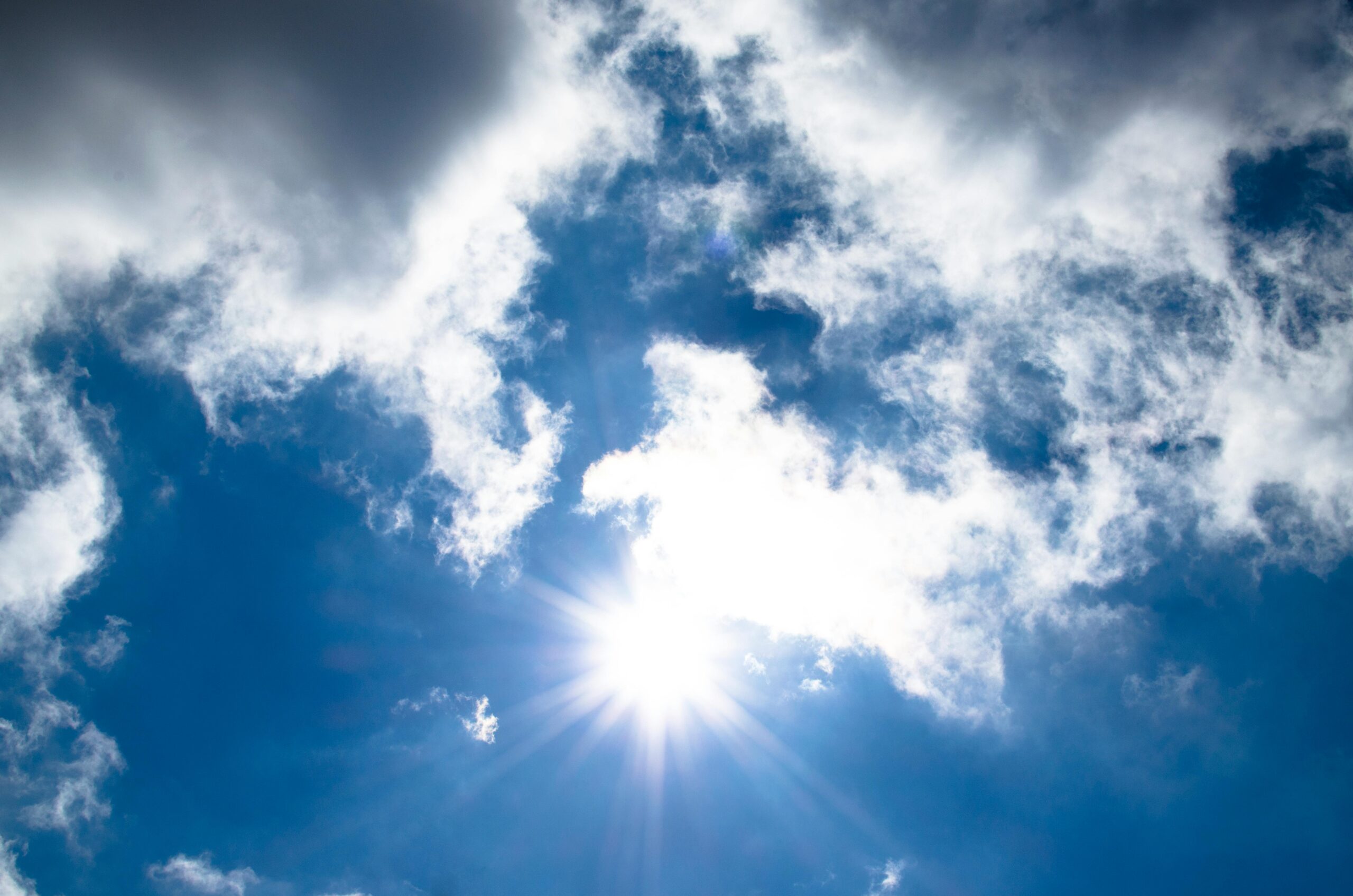 Rays of sunlight pierce through a cloudy sky, creating a striking contrast between light and shadow.