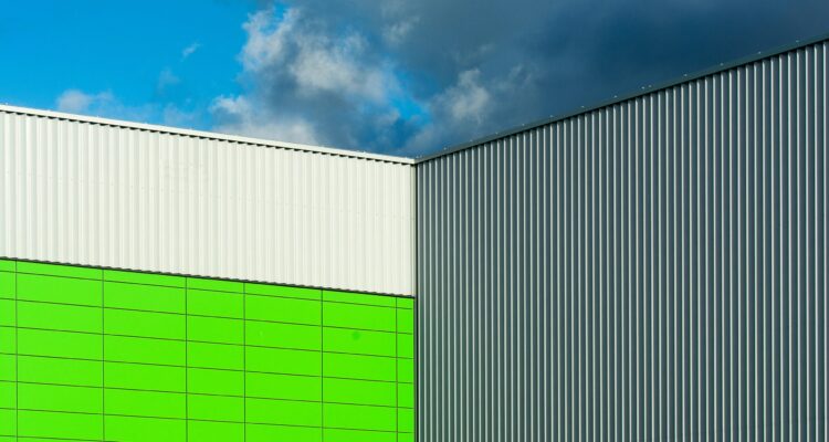 A green and white metal building stands against a clear blue sky, showcasing a vibrant contrast of colors.