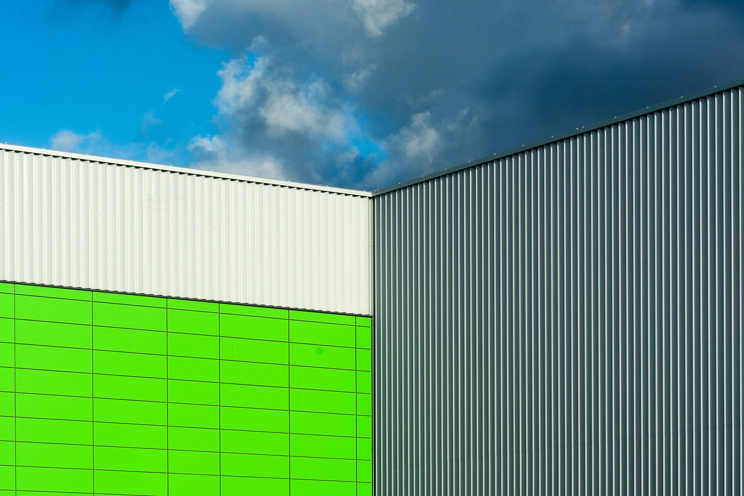 A green and white metal building stands against a clear blue sky, showcasing a vibrant contrast of colors.