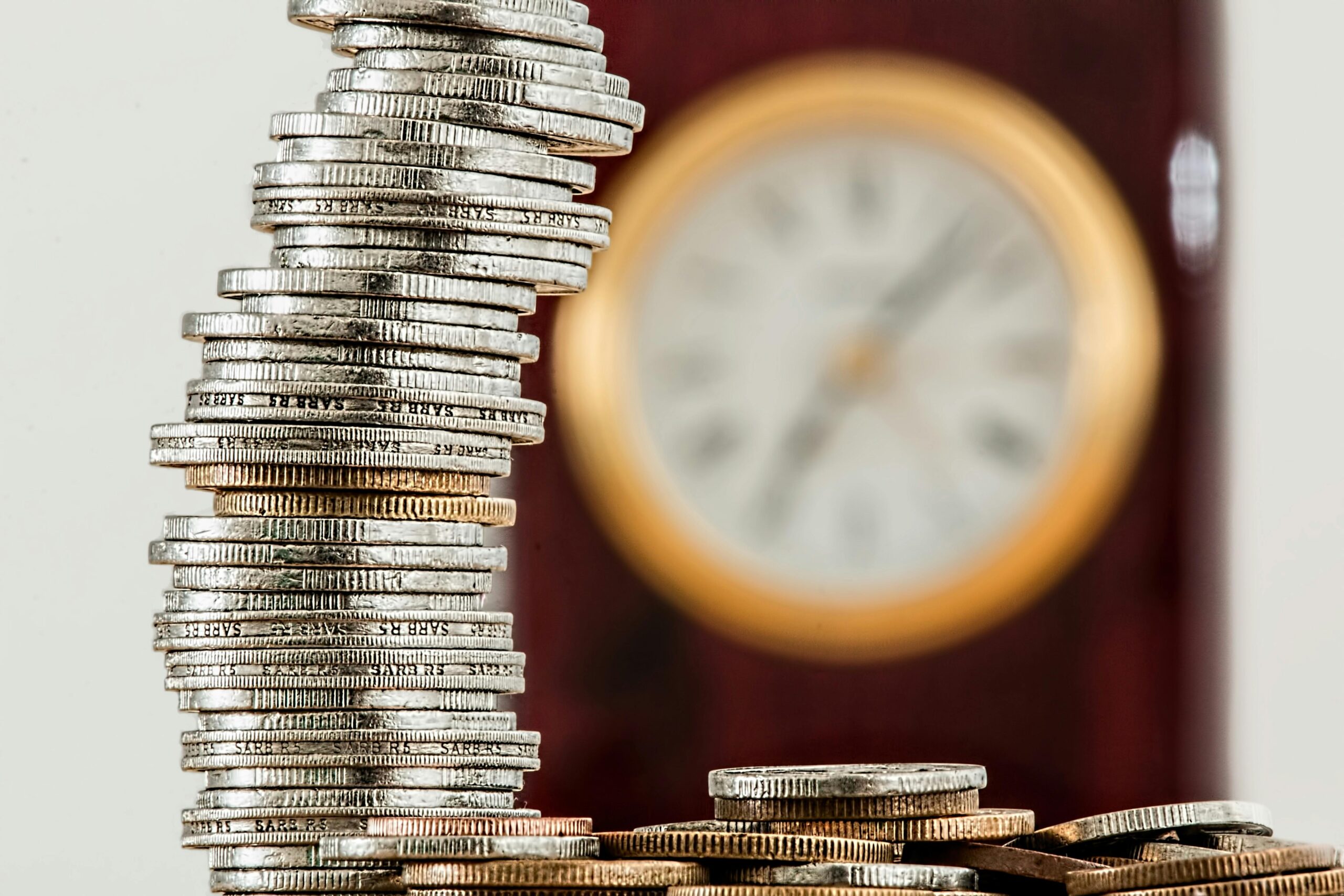 A stack of coins arranged neatly on a wooden table, showcasing their shiny surfaces and varying sizes.