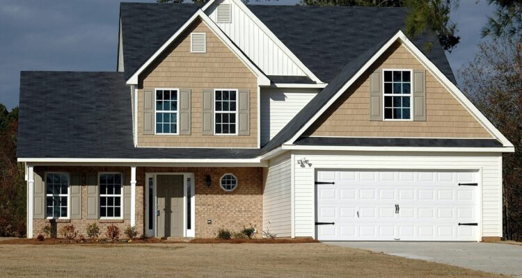 A two-story house featuring a garage and a spacious driveway, showcasing a welcoming residential environment.