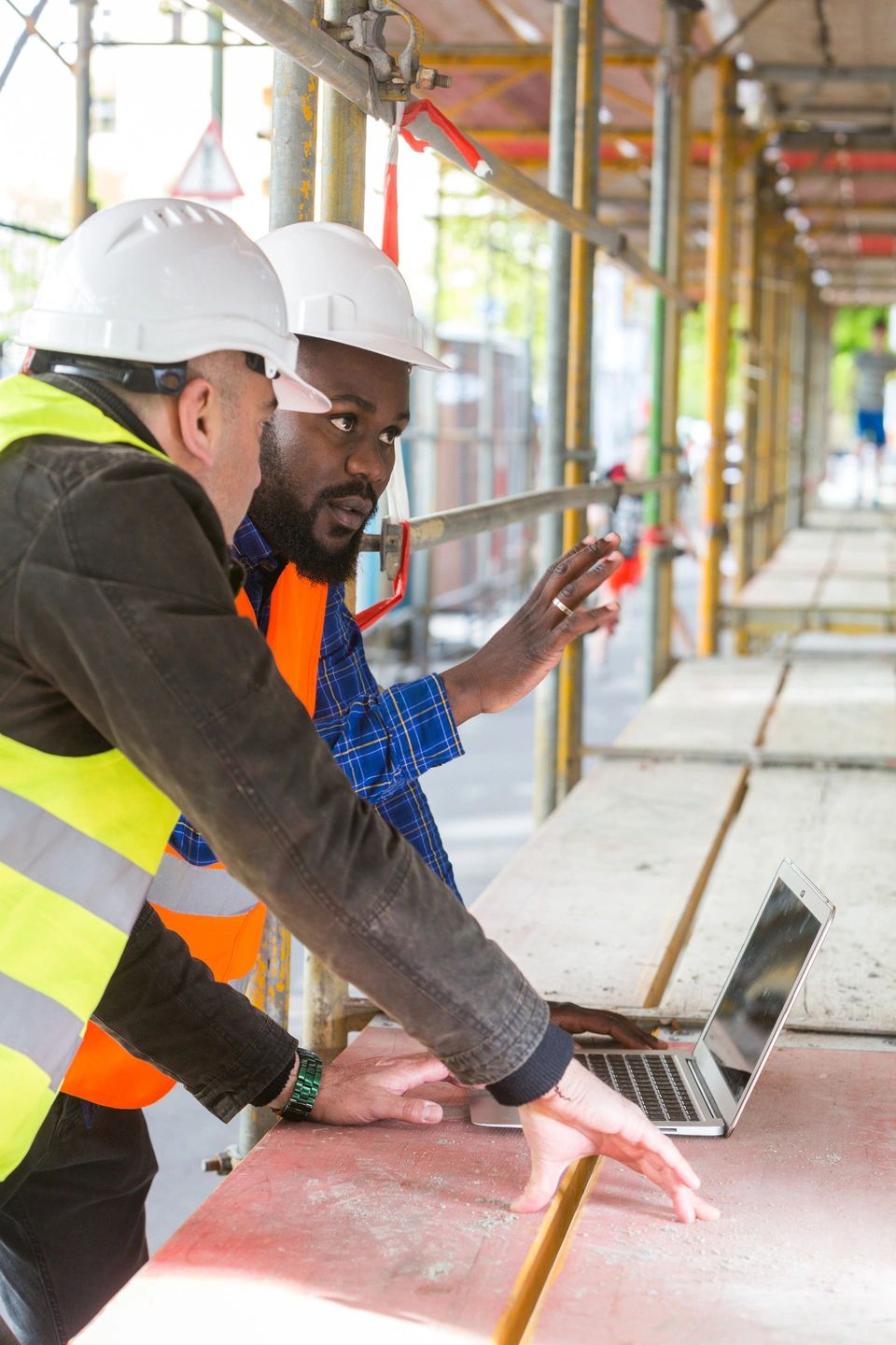 Two men in safety vests collaborate on a construction site, ensuring safety and efficiency in their work.