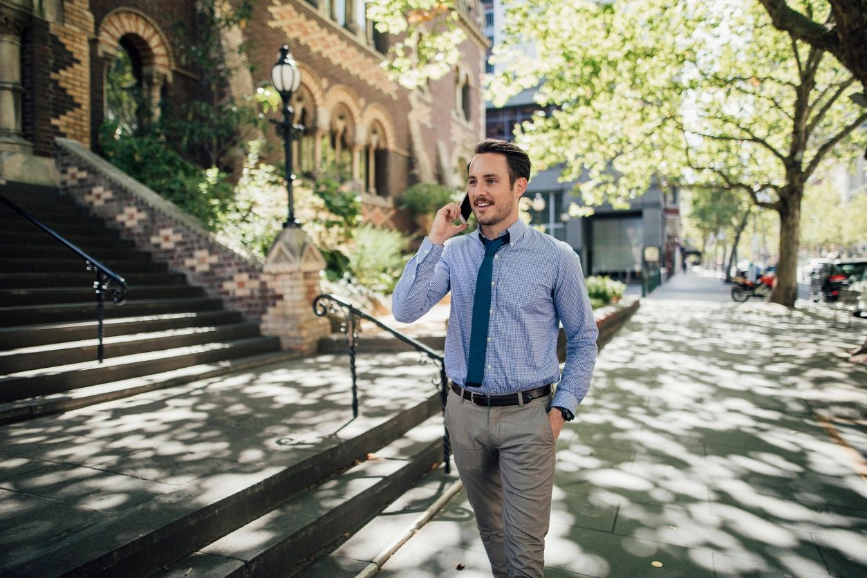 A man in a shirt and tie engaged in a conversation on his cell phone, exuding professionalism and focus.