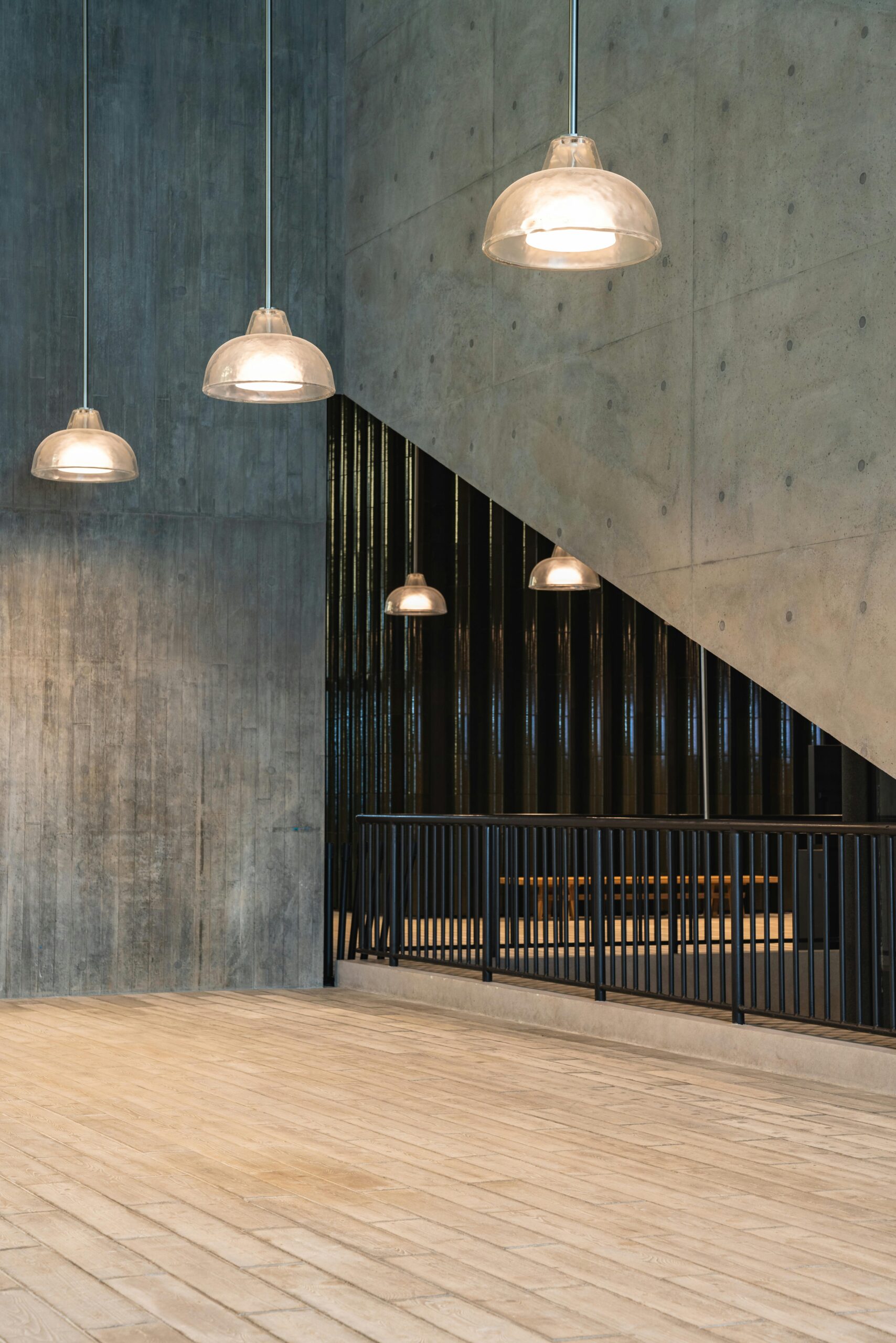 A room featuring a polished wooden floor and a microcement wall extending up to the ceiling, creating a warm and inviting atmosphere.